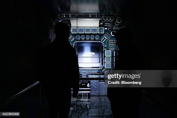 Visitors are silhouetted while standing in front of the Samsung Electronics Co. Logo displayed at the Semiconductor Rider experience at the company's...