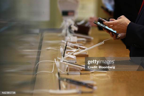 Visitor uses his mobile phone, top, as he tries out a Samsung Electronics Co. Galaxy Note 4 smartphone at the company's d'light flagship store in...