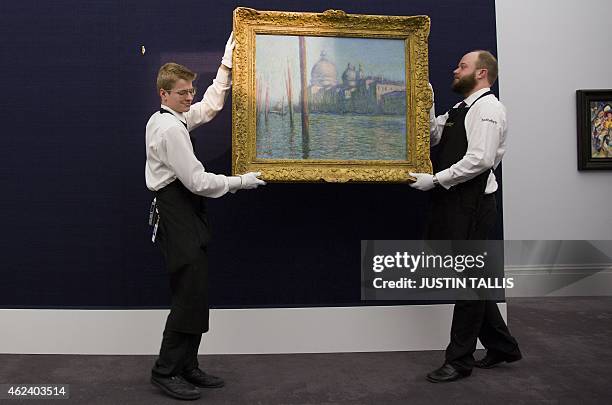 Employees of Sotherby's auction house position "Le Grand Canal", by Claude Monet during a press preview in London on January 28 ahead of the...