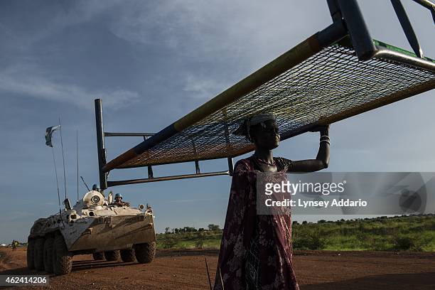 Woman walks past United Nations Peacekeepers on her way back to a camp for displaced people the day after heavy fighting in Bentiu, South Sudan, May...