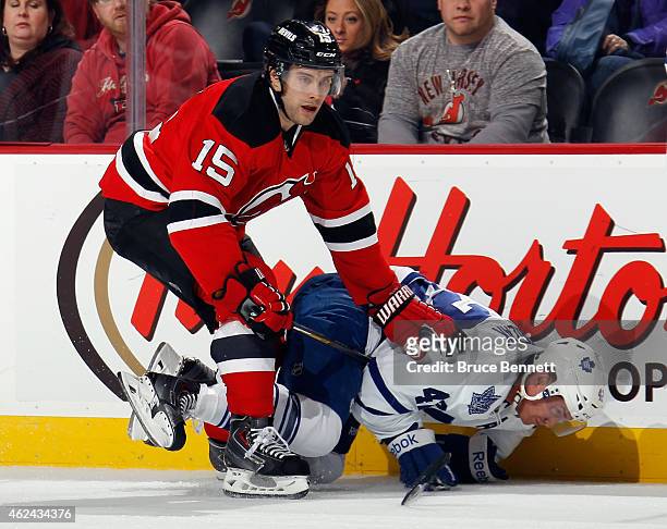Tyler Bozak of the Toronto Maple Leafs is tripped up by Tuomo Ruutu of the New Jersey Devils during the first period at the Prudential Center on...