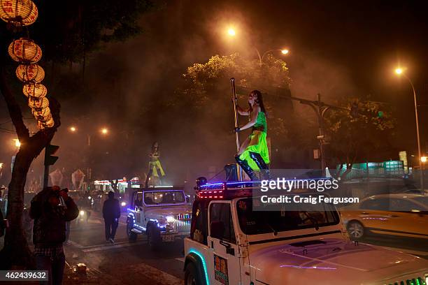 Pole dancers on top of vehicles strut their stuff outside a temple during a birthday festival for the god, Qingshan Wang.