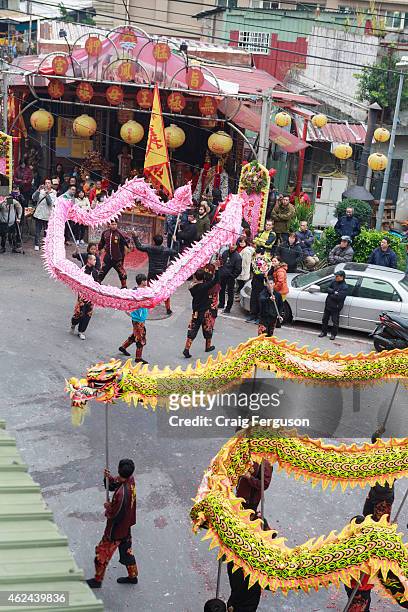 Two Chinese dragons are led toward a temple during birthday celebrations for a local God.