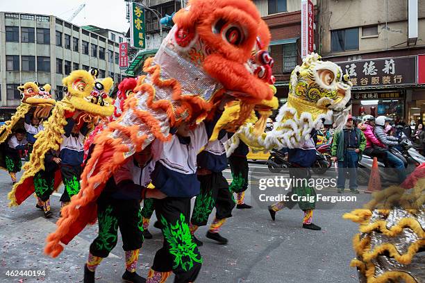 Chinese lions run down the street during a parade to celebrate the birthday of the god Qingshan Wang.