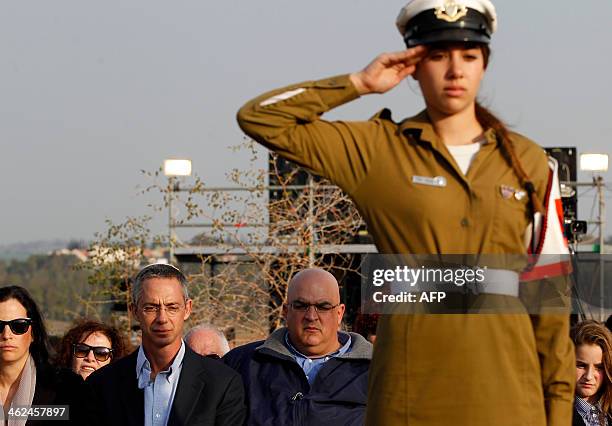 An Israeli soldier salutes in front of the sons of former Israeli Prime Minister Ariel Sharon, Gilad and Omri during the funeral of their father on...