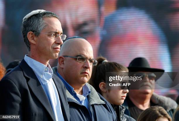 An Israeli soldier salutes in front of the sons of former Israeli Prime Minister Ariel Sharon, Gilad and Omri as they attend the funeral of their...