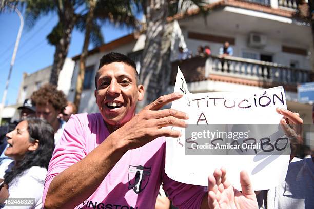 Man holds a banners reads "Dismissal of Gils Carbo" next to the funeral cortege carrying the remains of Argentine prosecutor Alberto Nisman heading...