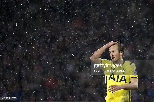 Tottenham Hotspur's English striker Harry Kane wipes his hair as snow falls during the English League Cup semi-final second leg football match...