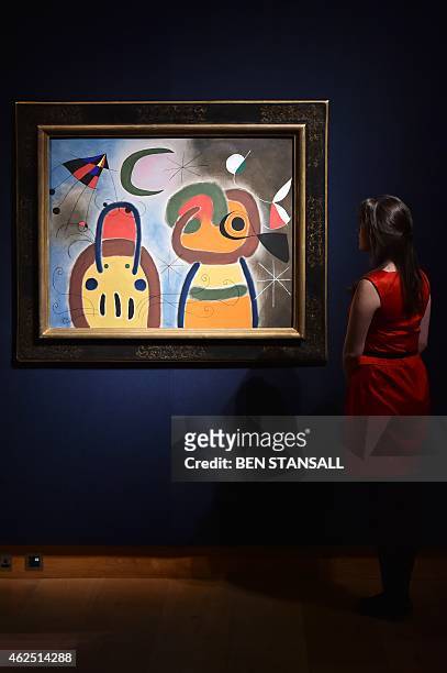 Staff member poses for pictures next to a painting by Joan Miro entitled "L'Oiseau au plumage deploye vole vers l'arbre argente," which is estimatd...