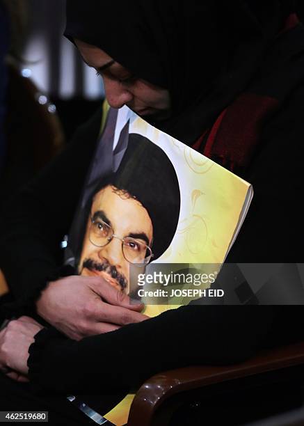 Shiite supporter holds a poster showing Hassan Nasrallah, the head of Lebanon's militant Shiite Muslim movement Hezbollah, as he addresses supporters...