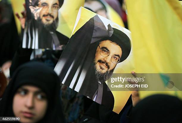 Shiite supporter holds a poster showing Hassan Nasrallah, the head of Lebanon's militant Shiite Muslim movement Hezbollah, as he addresses supporters...