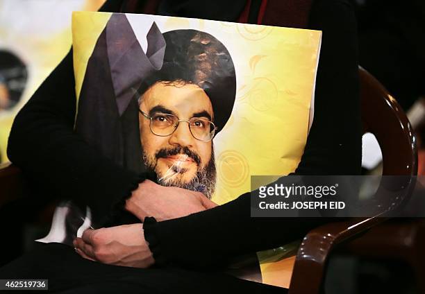 Shiite supporter holds a poster showing Hassan Nasrallah, the head of Lebanon's militant Shiite Muslim movement Hezbollah, as he addresses supporters...
