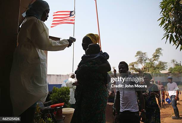 Regional health worker takes the temperature of a travelers at a highway checkpoint between Monserrado and Bomi counties on January 29, 2015 near...