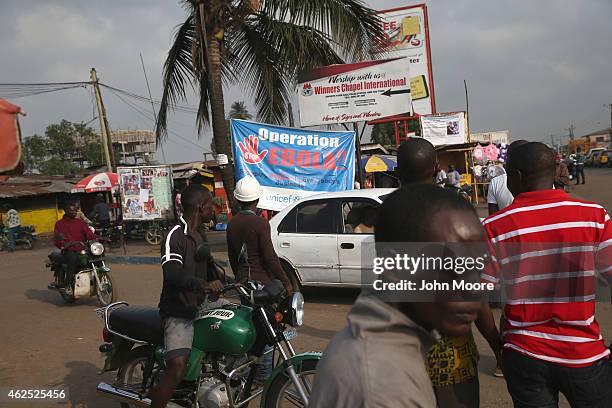 People walk past an Ebola awareness sign on January 29, 2015 near Monrovia, Liberia. Health workers are trying to prevent the movement of any...