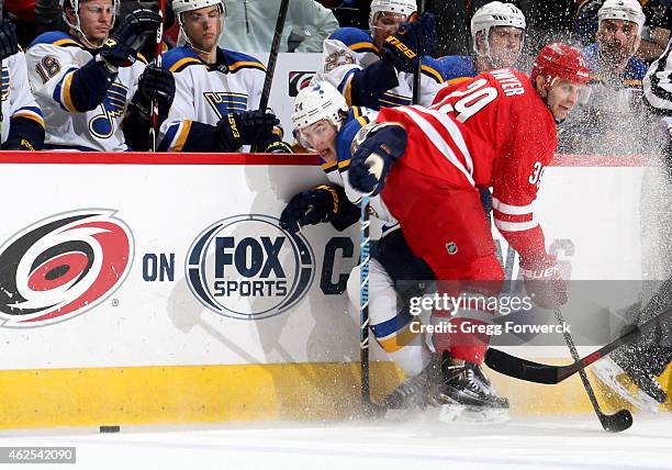 Patrick Dwyer of the Carolina Hurricanes collides along the bench with T.J. Oshie of the St. Louis Blues during their NHL game at PNC Arena on...