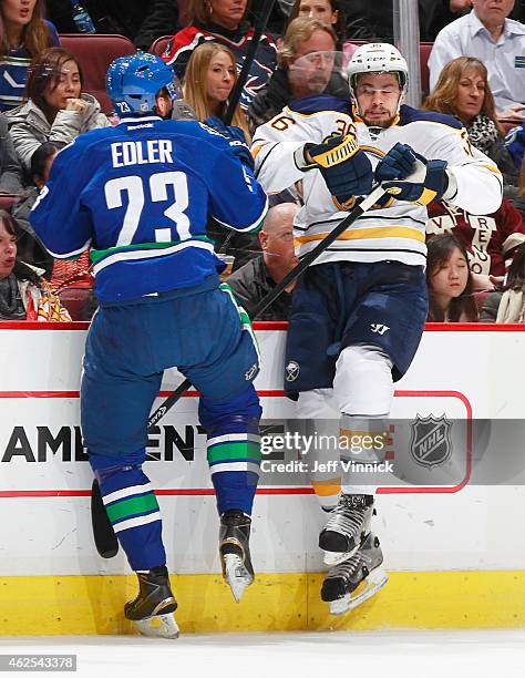 Alexander Edler of the Vancouver Canucks checks Patrick Kaleta of the Buffalo Sabres during their NHL game at Rogers Arena January 30, 2015 in...