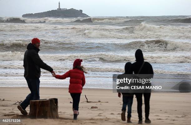 People walk on the seashore with strong wind at Somo beach, near Santander, on January 31, 2015. Fierce waves were pounding seafronts and fishing...