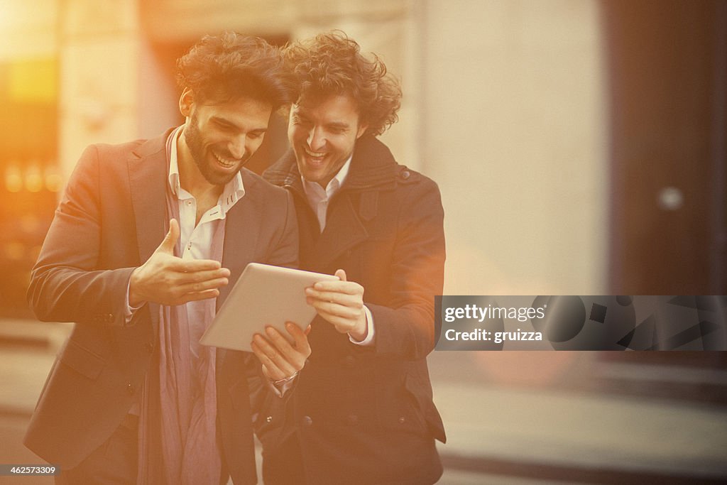 Two handsome guys watching on a digital tablet