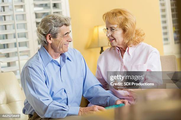 senior man receiving prescription medication from wife at home - child proofing stock pictures, royalty-free photos & images