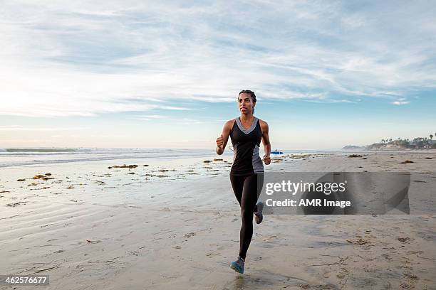 frau laufen am strand - läufer dramatisch stock-fotos und bilder
