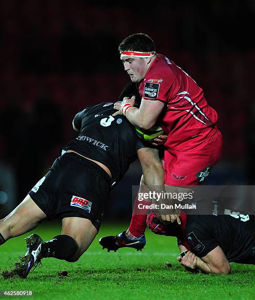 Wyn Jones of Scarlets is tackled by Leo Halavatau and Sean Cox of London Irish during the LV= Cup match between Scarlets and London Irish at Parc y...