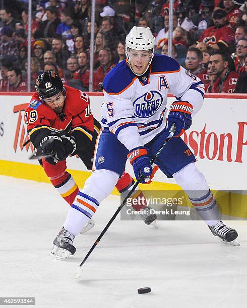 David Jones of the Calgary Flames tries to check Mark Fayne of the Edmonton Oilers during an NHL game at Scotiabank Saddledome on January 31, 2015 in...