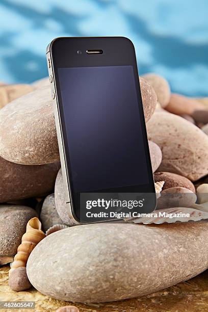 An Apple iPhone 4 photographed on a coastal-style background, taken on April 18, 2013.