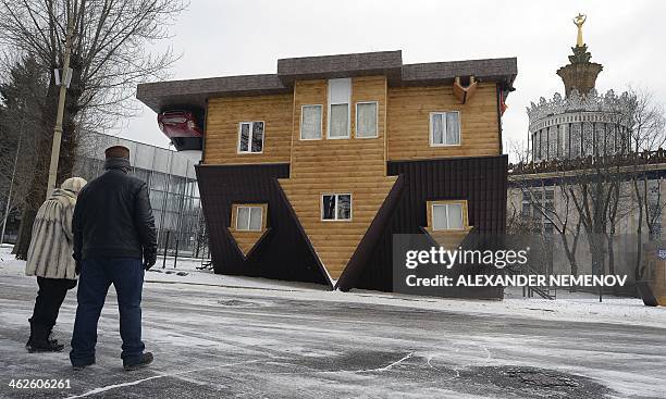 People look at an "upside-down house" attraction displayed at the VVTs the All-Russia Exhibition Center in Moscow, on January 14, 2014. AFP PHOTO /...