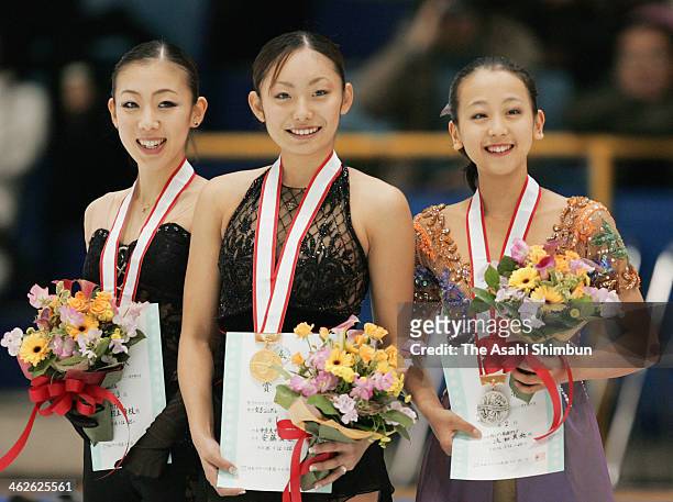 Winners Miki Ando , Mao Asada , and Fumie Suguri pose for photographs on the podium after their ladies free proogram during All Japan Figure Skating...
