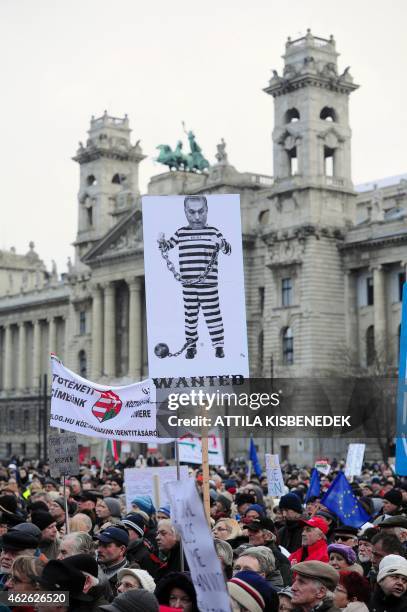 Protesters hold a banner featuring Hungarian Prime Minister Victor Orban in front of the building of the parliament in Budapest downtown on February...