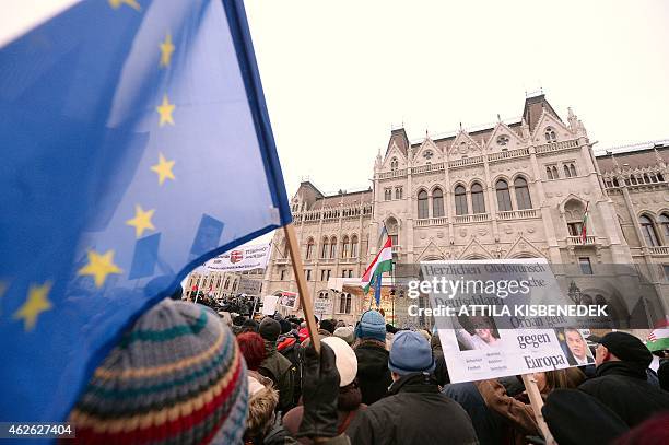 Protesters hold an EU flag and a photo of German chancellor Angela Merkel in front of the building of the parliament in Budapest downtown on February...