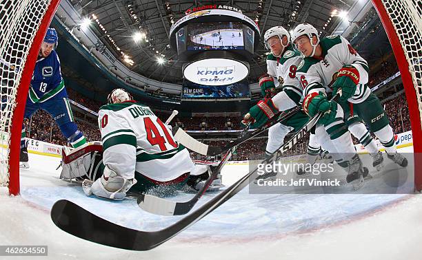 Mikko Koivu and Jared Spurgeon of the Minnesota Wild ensure a shot by Nick Bonino of the Vancouver Canucks doesn't slide behind Devan Dubnyk of the...