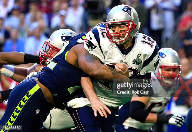 Michael Bennett of the Seattle Seahawks hits Tom Brady of the New England Patriots in the first quarter during Super Bowl XLIX at University of...