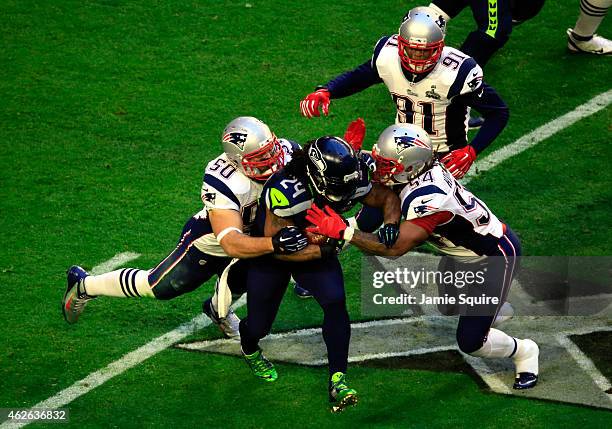 Marshawn Lynch of the Seattle Seahawks is tackled by Rob Ninkovich and Dont'a Hightower of the New England Patriots during Super Bowl XLIX at...