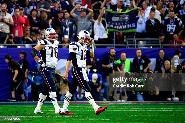 Tom Brady of the New England Patriots walks to the sideline after an interception alongside team mate Sebastian Vollmer of the New England Patriots...