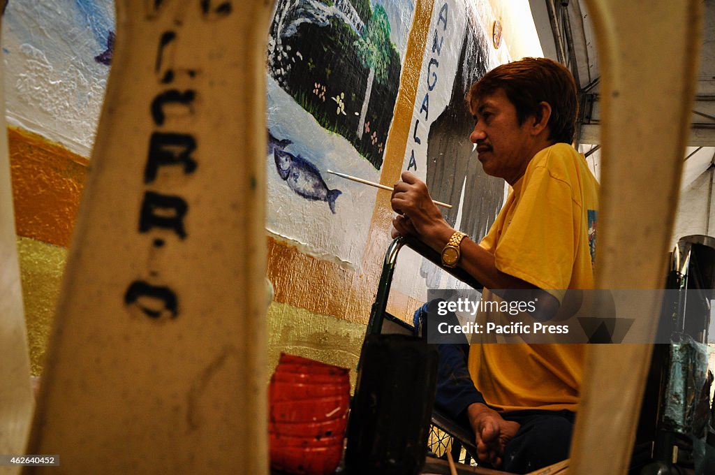 A PWD artist paints a mural as he participates during the...