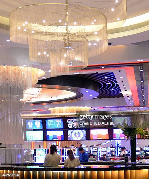 Restaurant employees work next to the casino of the newly-opened City of Dreams mega-casino chain in Manila on February 2, 2015. Six gleaming golden...
