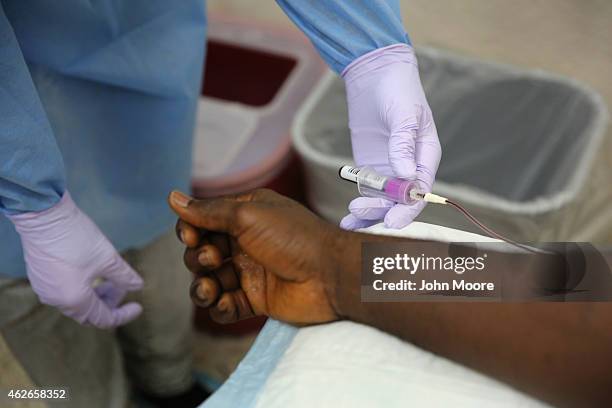 Nurse takes a blood sample from Emmanuel Lansana the first person to take part in the Ebola vaccine study being conducted at Redemption Hospital,...