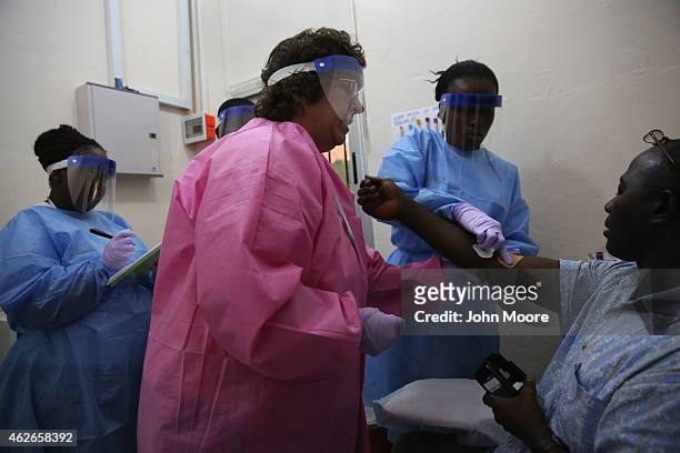 Nurses take a blood sample from Emmanuel Lansana the first person to take part in the Ebola vaccine trials being conducted at Redemption Hospital,...