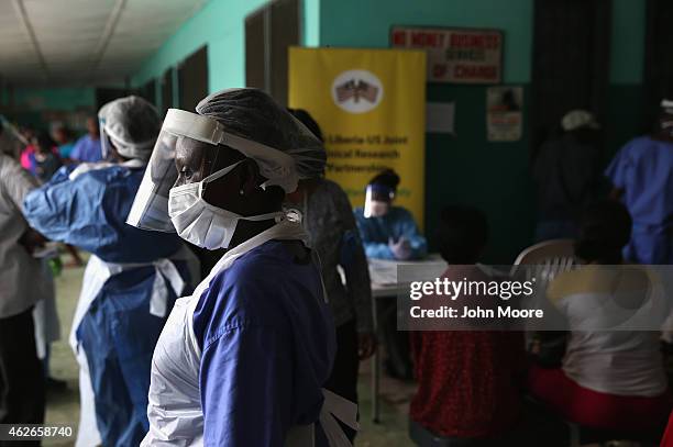 Health workers in protective clothing await patients in the outpatient lounge of Redemption Hospital, formerly an Ebola holding center, on February...