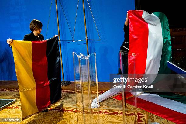 Two women roll up the German and Hungarian national flags after the end of a press conference of German Chancellor Angela Merkel and Hungarian Prime...