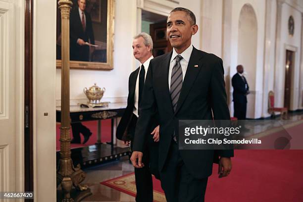 President Barack Obama and National Hockey League champions Los Angeles Kings Head Coach Darryl Sutter walk into the East Room of the White House...
