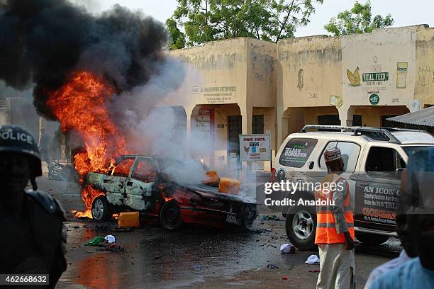 Car is on fire after a suicide bombing which was staged by a suspected female suicide bomber near a campaign rally at Pantami Stadium attended by...