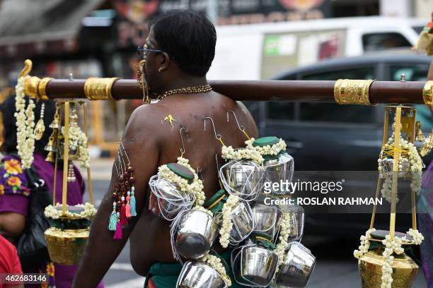 Hindu devotee with ornamental facial and body piercings carries offerings of milk along a procession route in Singapore's Little India district as...