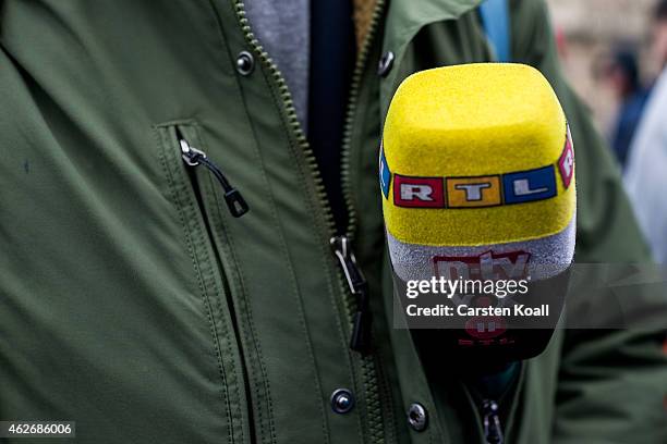 Television journalist holds a microphone of RTL in his pocket as he waits for the visit of German Chancellor Angela Merkel on February 2, 2015 in...