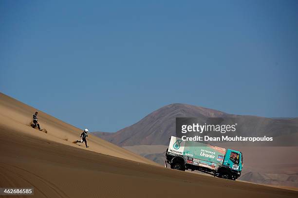 Hans Stacey drives as Detlef Ruf and Bernard Der Kinderen of the Netherlands run for the truck for Iveco Team De Rooy 2014 after releasing it from...