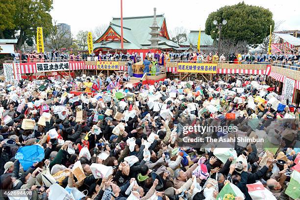 Actor Tetsuji Tamayama and actress Charlotte Kate Fox throw beans while people try to catch them during a bean scattering ceremony to mark the end of...