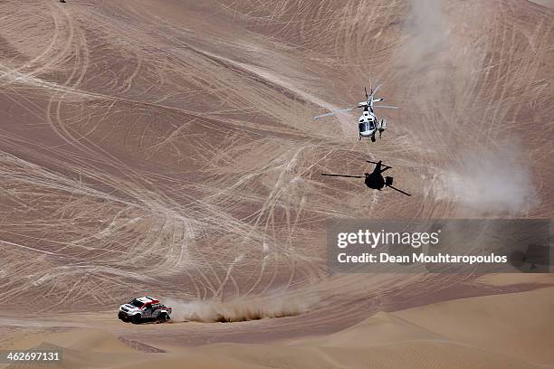 Giniel De Villiers of South Africa and Dirk Von Zitzewitz of Germany for Imperial Toyota compete as the helicopter flies overhead in stage 9 during...