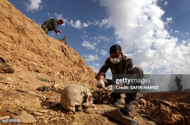 An Iraqi man inspects on February 3 the remains of members of the Yazidi minority killed by the Islamic State jihadist group after Kurdish forces...