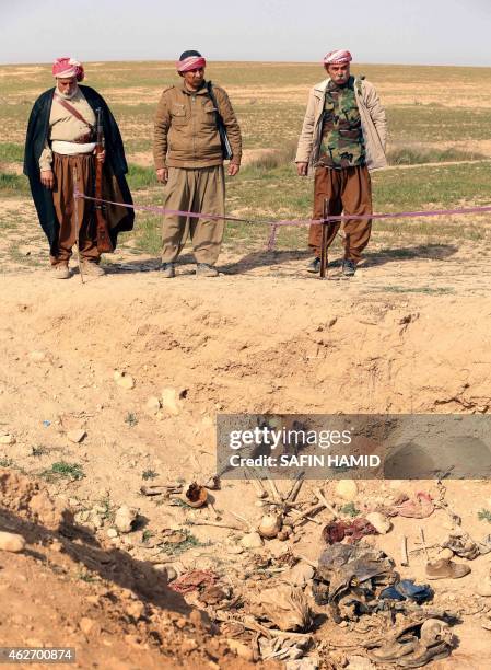 Members of the Yazidi minority look at the remains of people killed by the Islamic State jihadist group as they search for clues that might lead them...